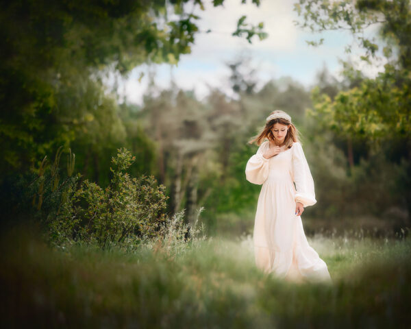 portret van een jonge vrouw in een dromerige witte jurk in het groene bos tijdens de lente door natuurlijk licht fotograaf Willie Kers uit Apeldoorn